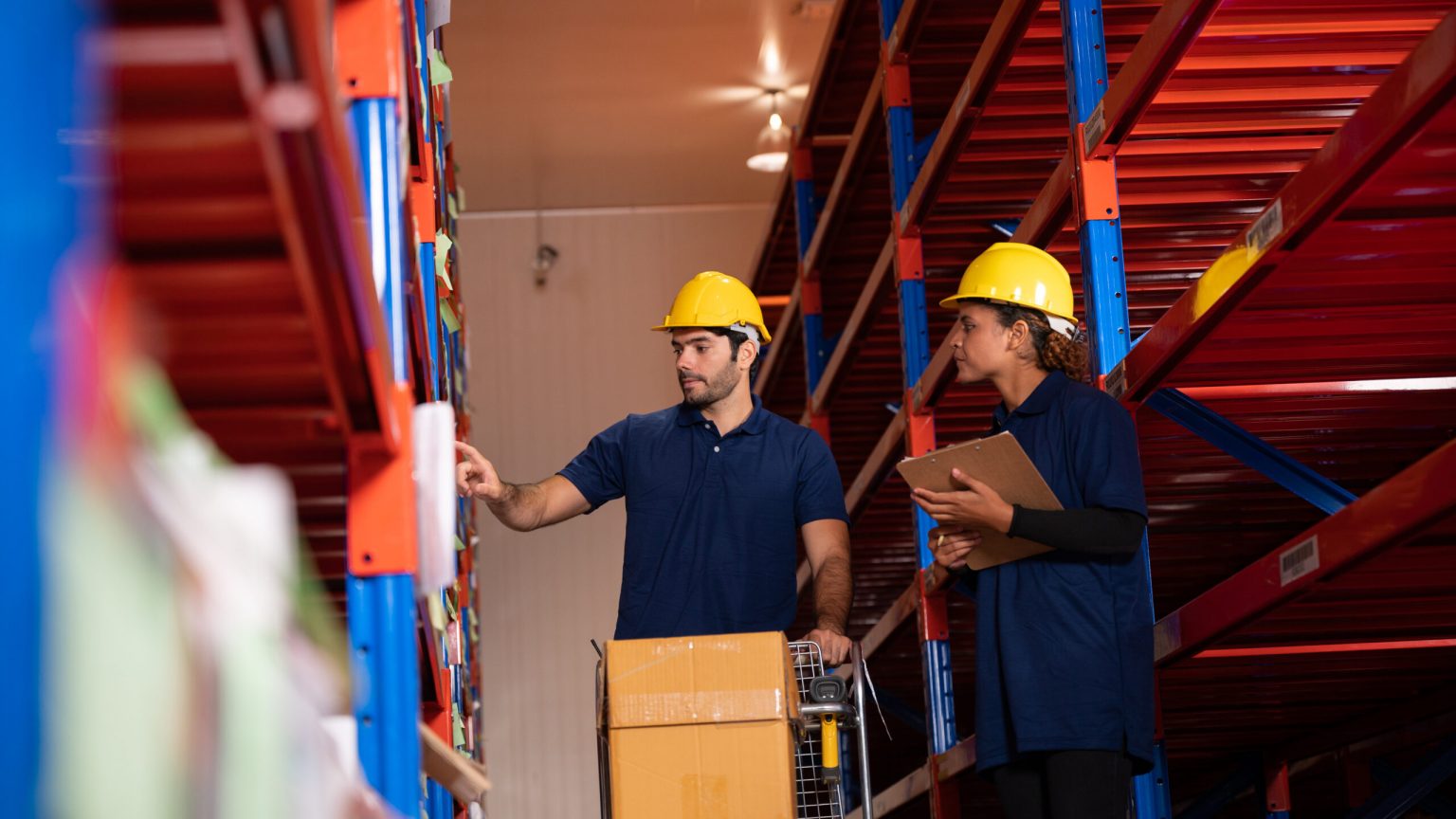 warehouse workers logistic team wearing hardhats to working in aisle between tall racks with packed goods, While inspecting industrial plants and warehouses for international shipping businesses